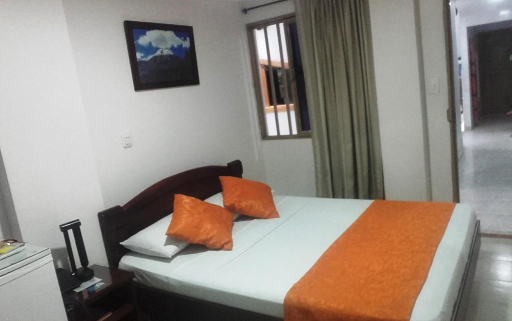 a bedroom with a bed with orange pillows on it at Hotel Center in Ibagué