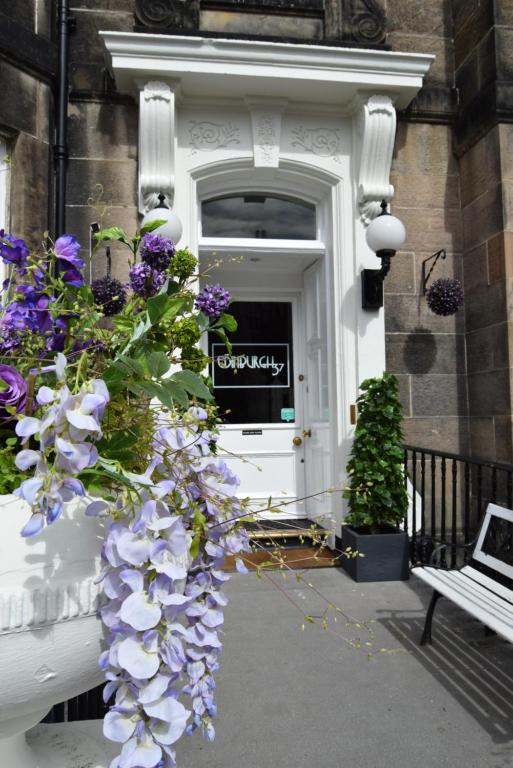 um vaso cheio de flores roxas na frente de uma porta em Edinburgh37 em Edimburgo