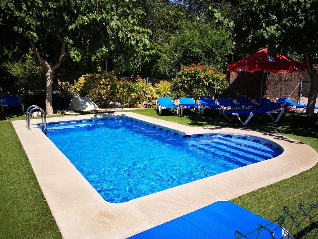 uma piscina com mesas azuis e cadeiras num quintal em Casas Rurales Huerto Del Abuelito em Valdeganga