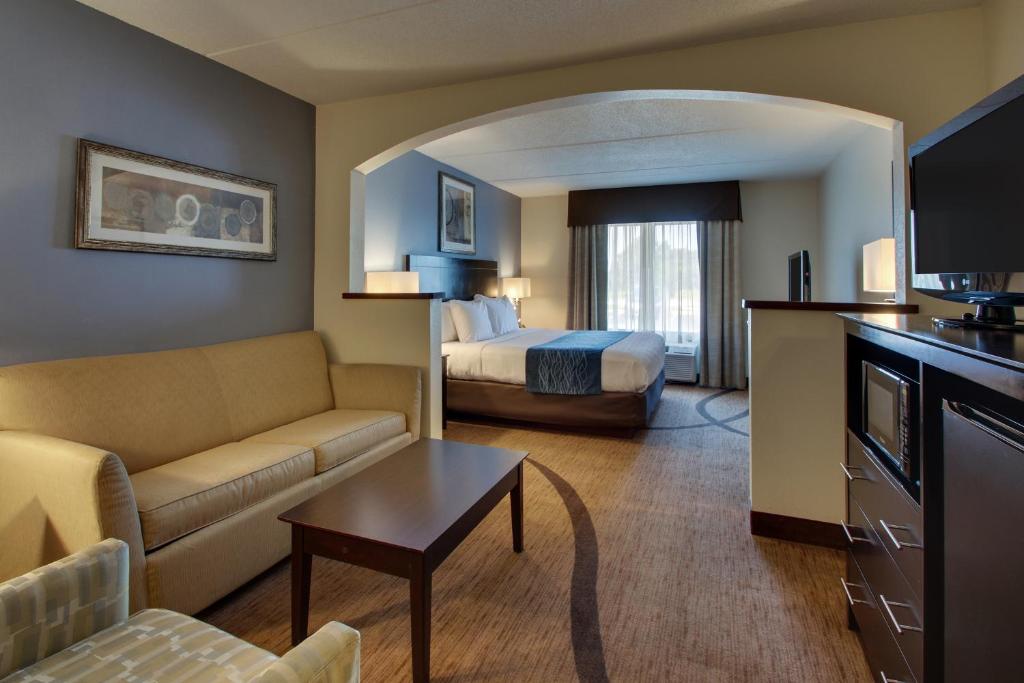 Habitación de hotel con cama y sala de estar. en Wingfield Inn & Suites en Owensboro