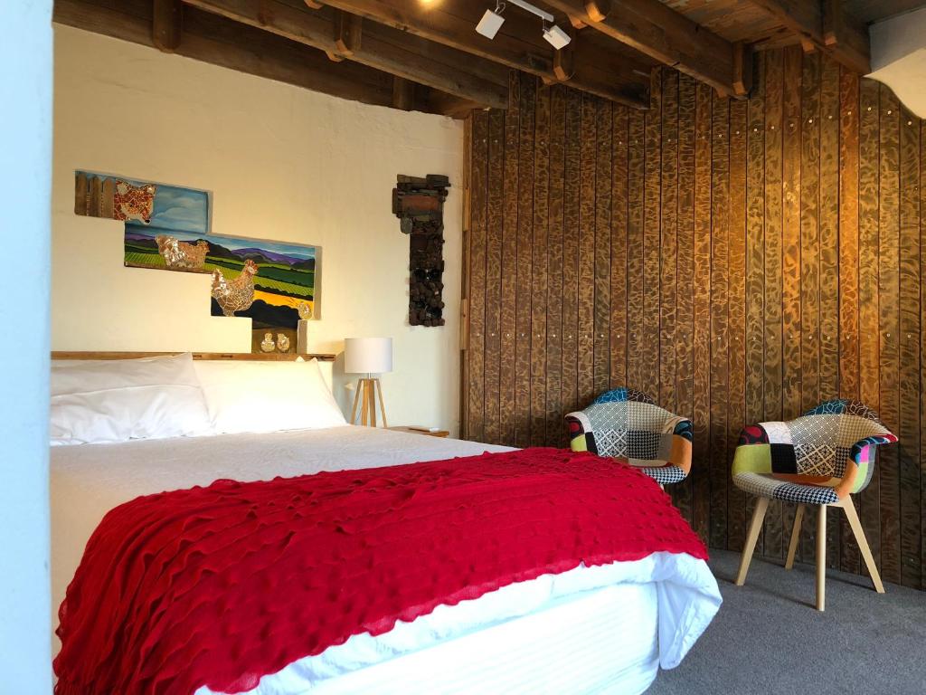 1 dormitorio con 1 cama con manta roja y 2 sillas en Bed in a Shed Too, en Watervale