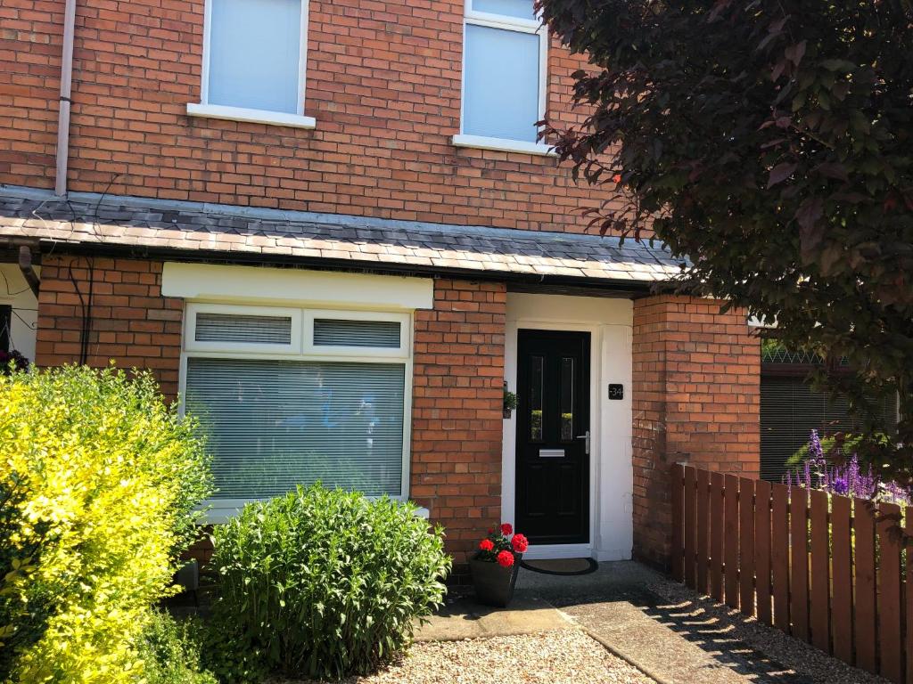 une maison en briques rouges avec une porte noire dans l'établissement Belfast Holiday Home, à Belfast