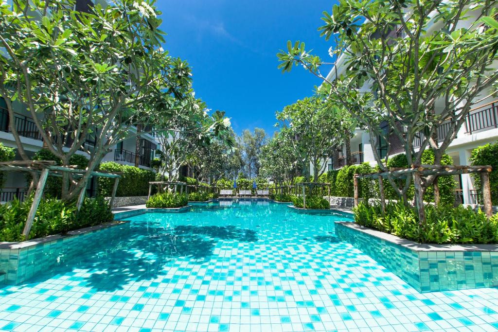 a swimming pool in the middle of a building with trees at The Title Boutique Phuket in Rawai Beach