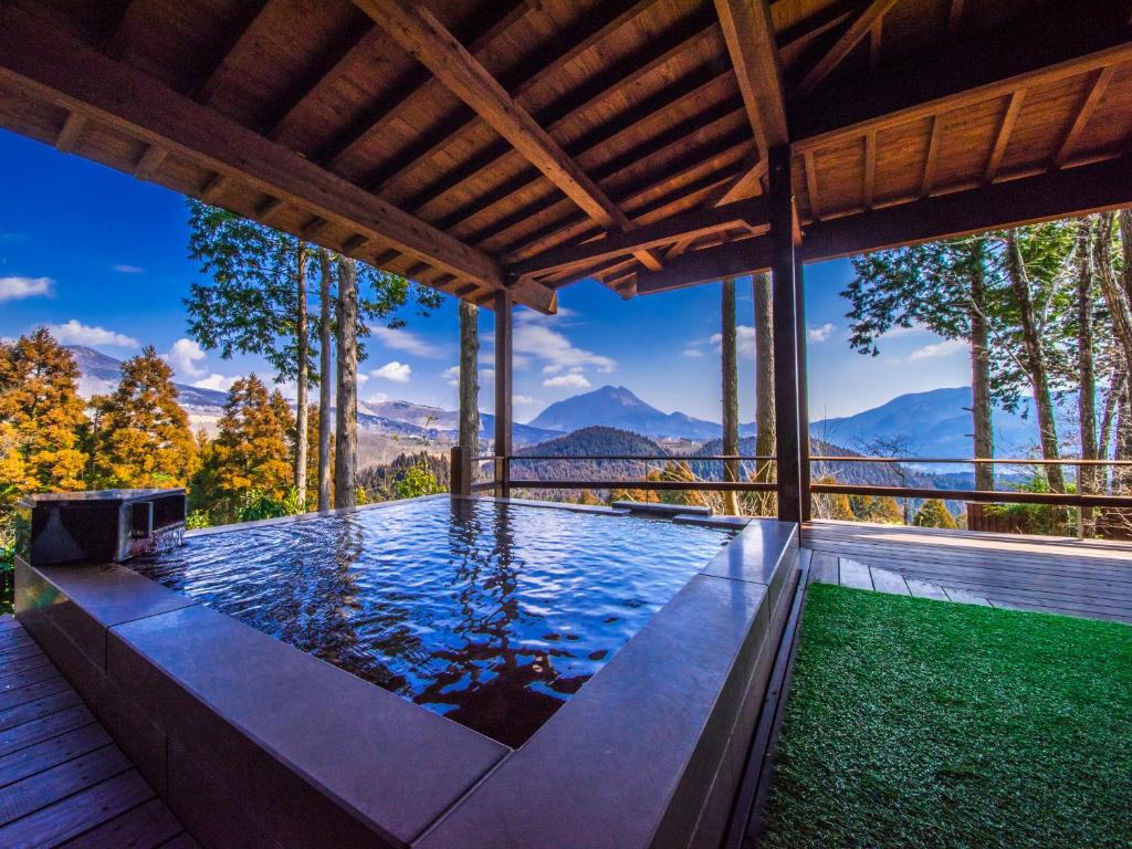 an infinity pool in a house with mountains in the background at Kusayane no yado Ryunohige in Yufuin