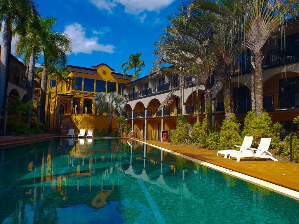 una piscina frente a un edificio con palmeras en Palm Royale Cairns, en Cairns