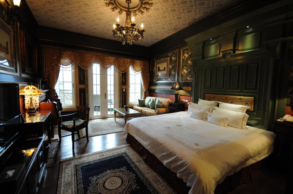 a bedroom with a large bed and a chandelier at The Old England Manor in Ren&#39;ai