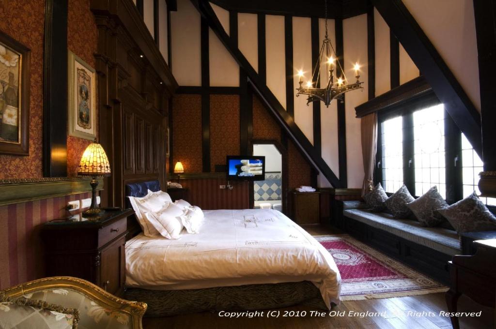 a bedroom with a bed in a room with a staircase at The Old England Manor in Ren&#39;ai