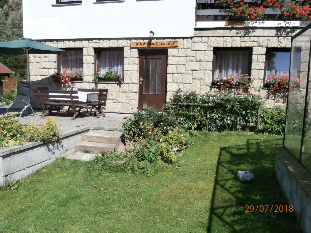 a house with a bench and flowers in the yard at Apartman Aya in Janov nad Nisou