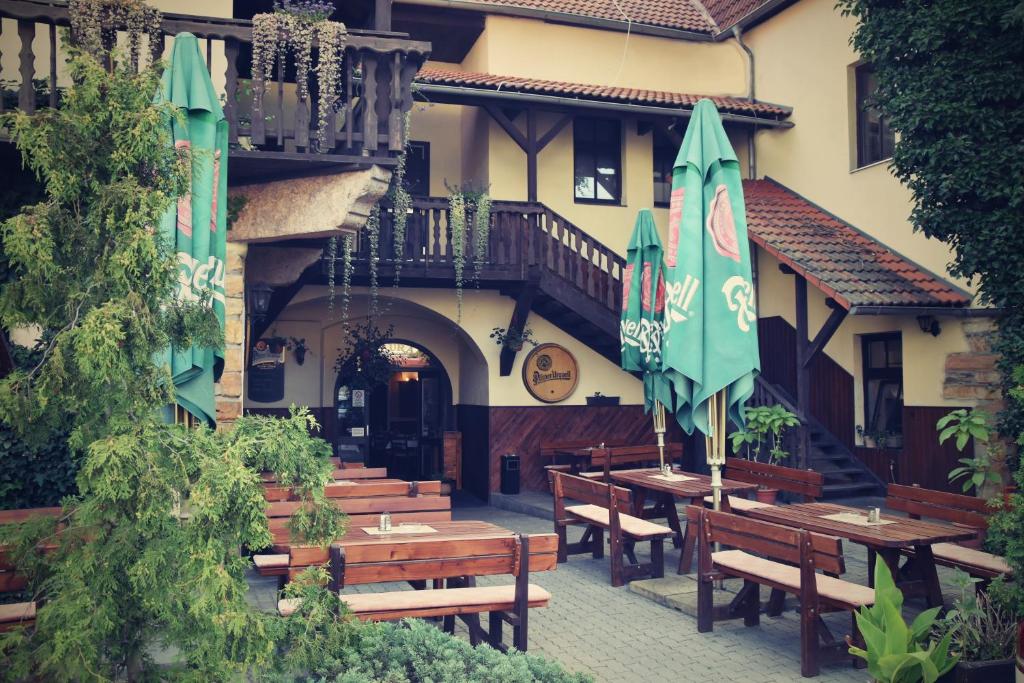 un patio con bancos de madera y sombrillas frente a un edificio en Hotel U Dvou medvídků en Chomutov