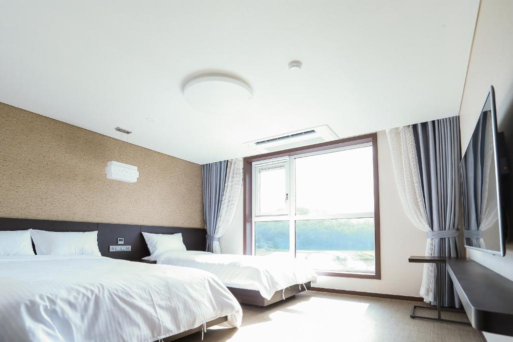 a hotel room with two beds and a window at Jeju Stay in Sungsan in Seogwipo