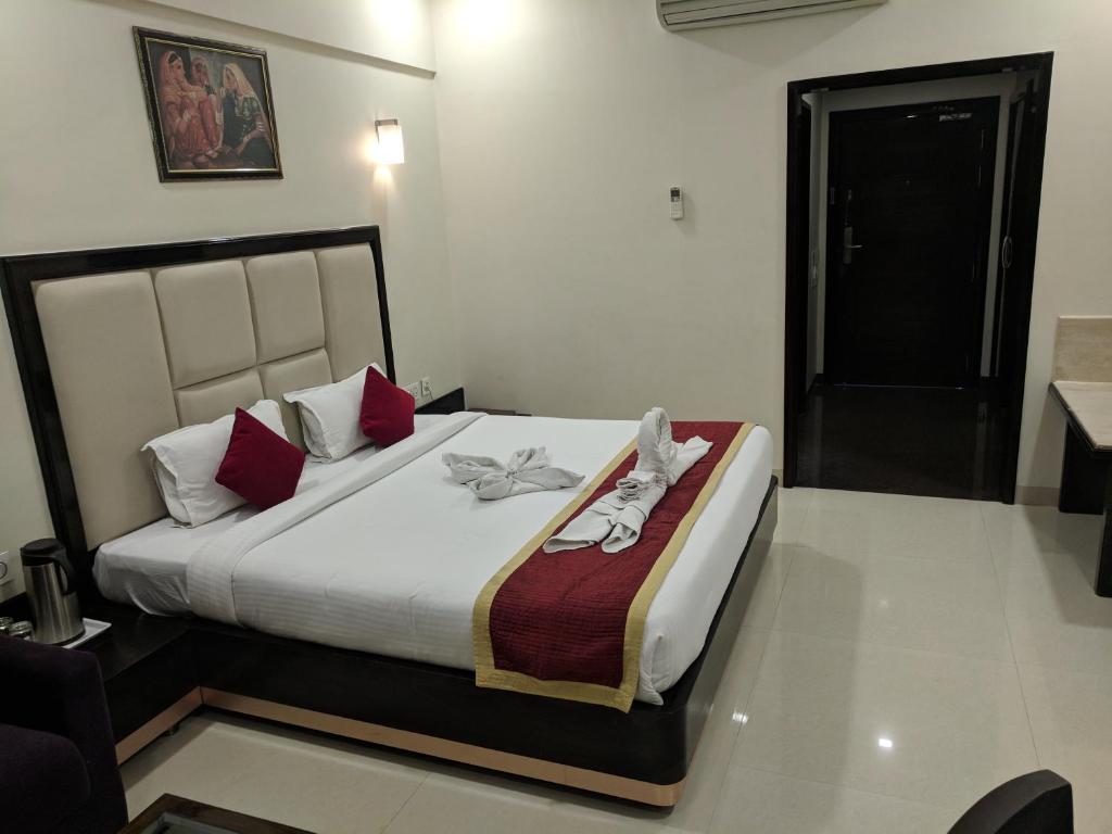 ein Schlafzimmer mit einem großen Bett mit roten Kissen in der Unterkunft Chandra Imperial in Jodhpur