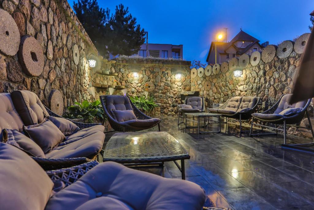 a patio with chairs and tables and a stone wall at Trys Apartamentai in Palanga