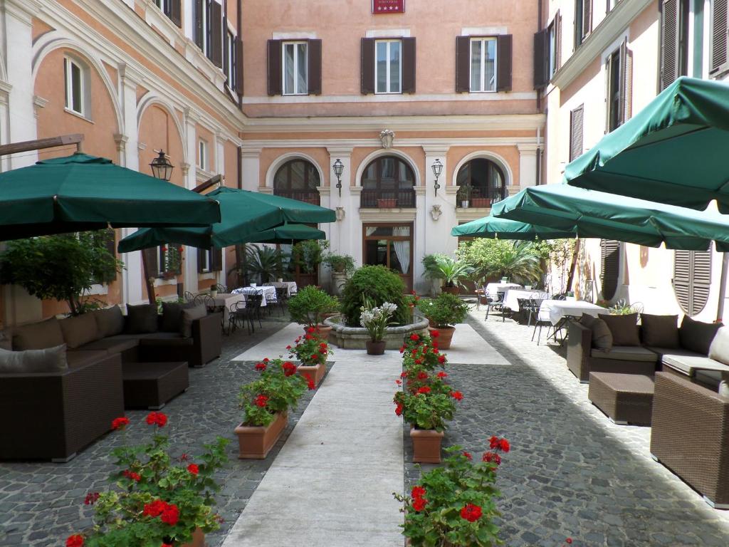 un patio con mesas, sombrillas y flores en Relais Hotel Antico Palazzo Rospigliosi, en Roma