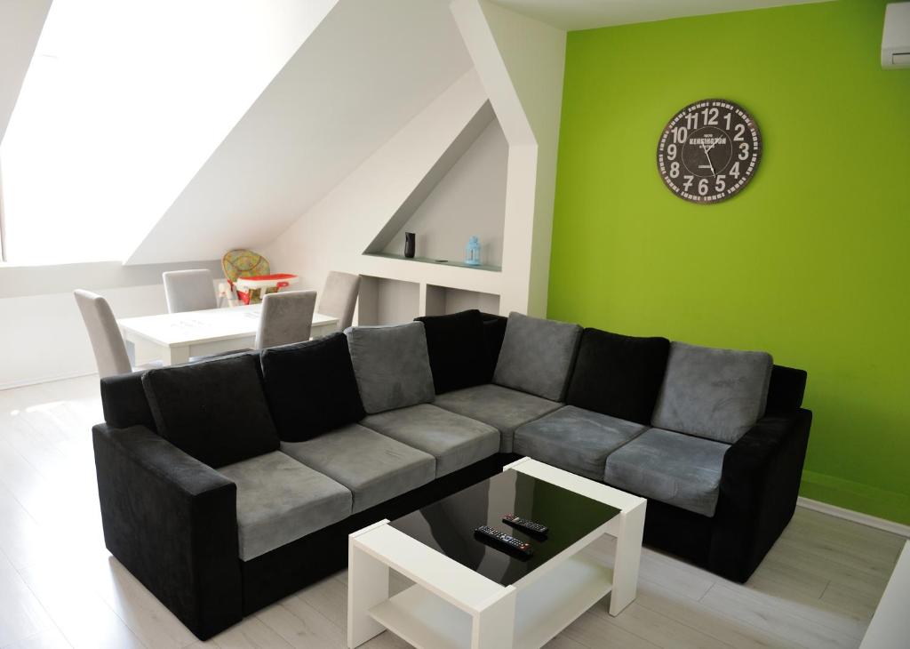 ein Wohnzimmer mit einem Sofa und einer Uhr an einer grünen Wand in der Unterkunft Apartment Vatra in Sarajevo