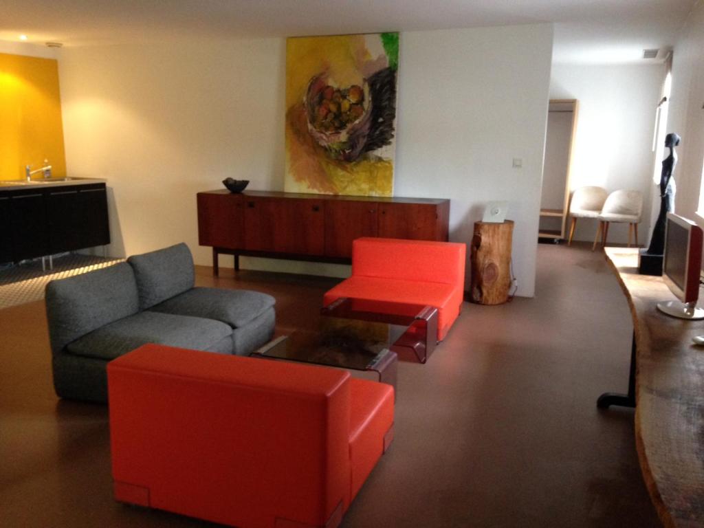 uma sala de estar com um sofá e cadeiras vermelhas em B&B Bloc G em Carcassonne