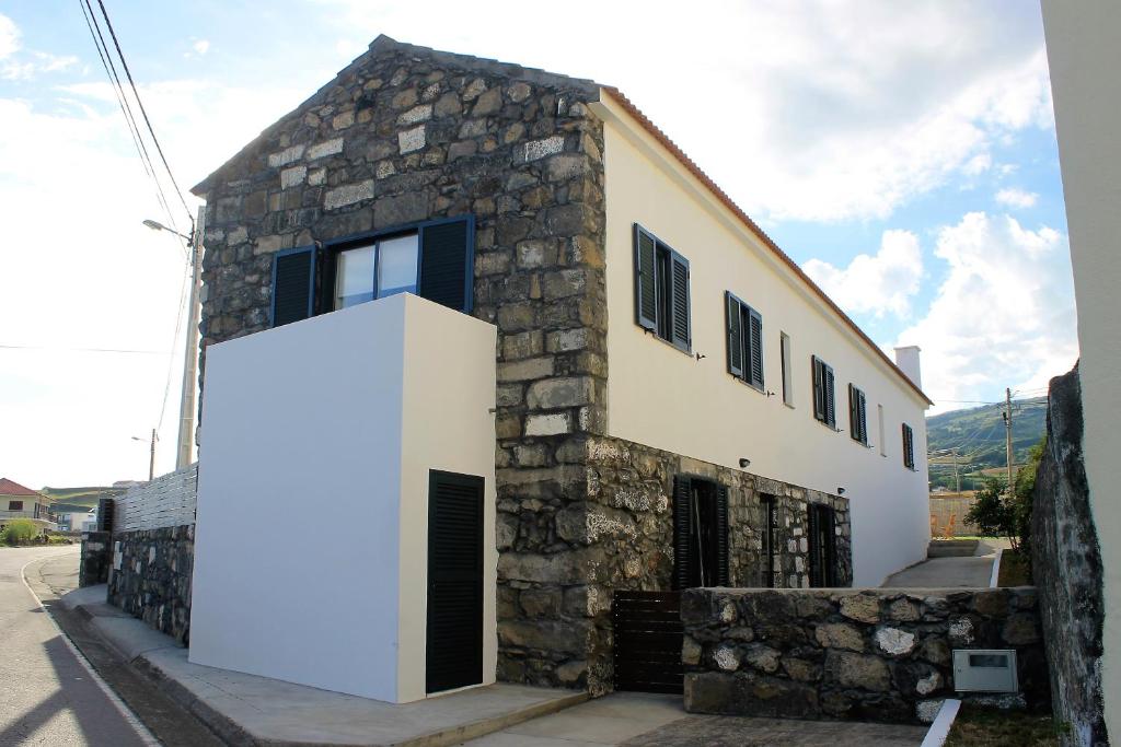 a stone house with a white door on the side of it at Refúgio in Horta
