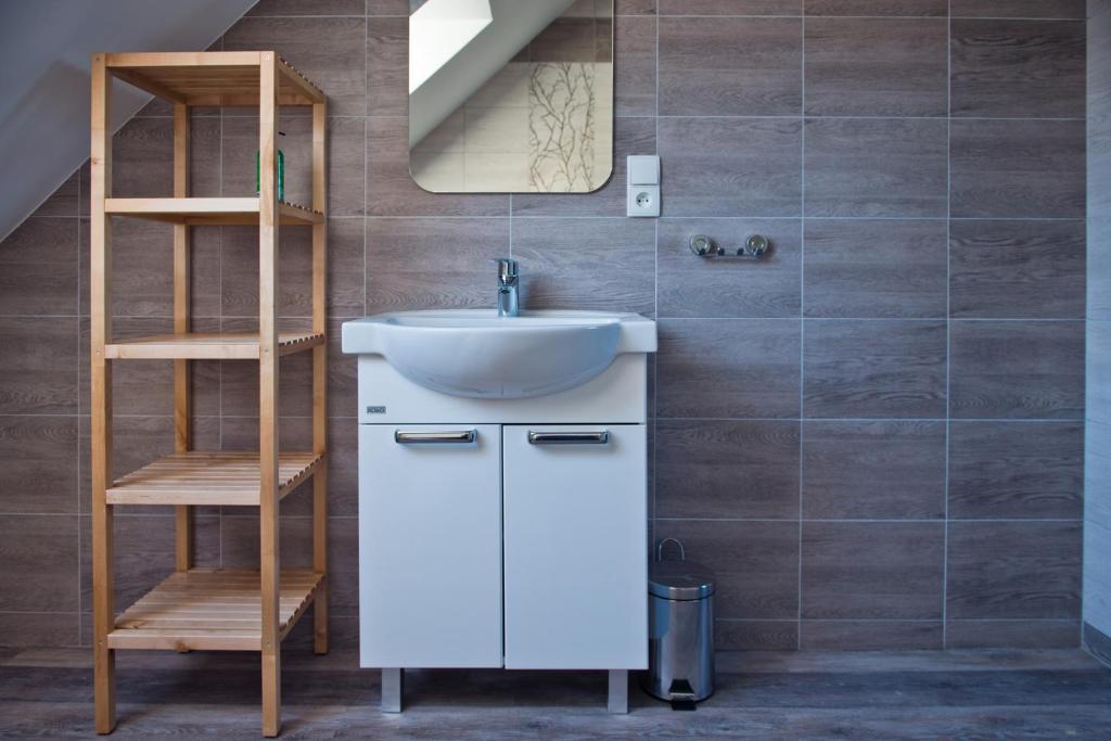 a bathroom with a sink and a wooden shelf at Apartamenty Buczyna w Sierakowie in Sieraków