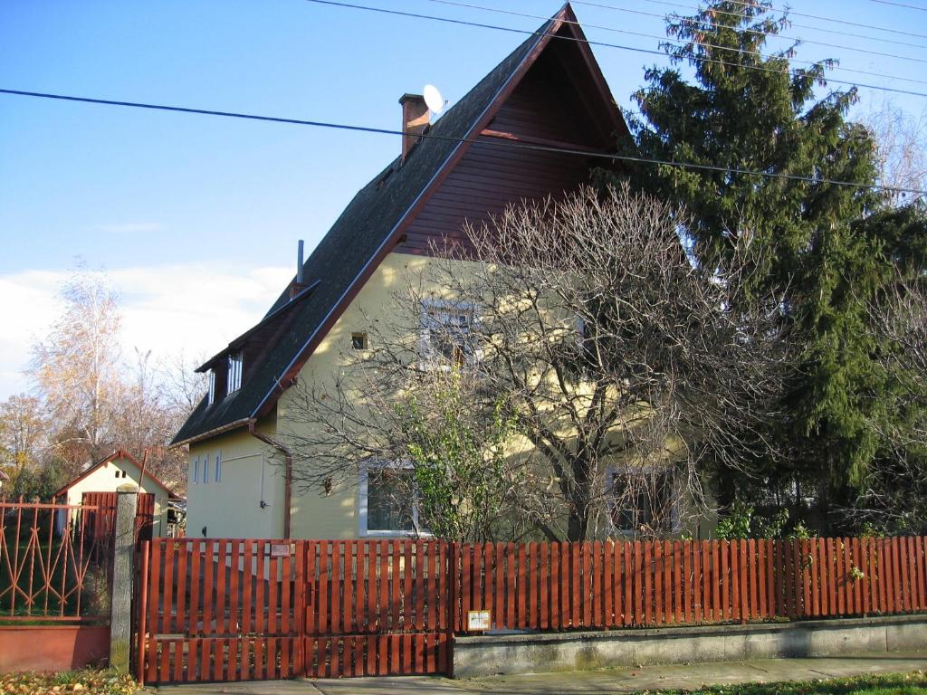 歐羅什哈佐的住宿－Alpesi Vendégház，前面有红墙的房子