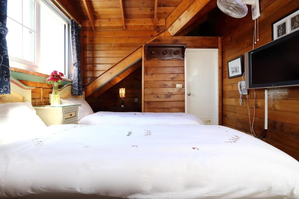 two beds in a room with wooden walls and a tv at Cingjing Hanging Garden &amp; Resort in Ren&#39;ai