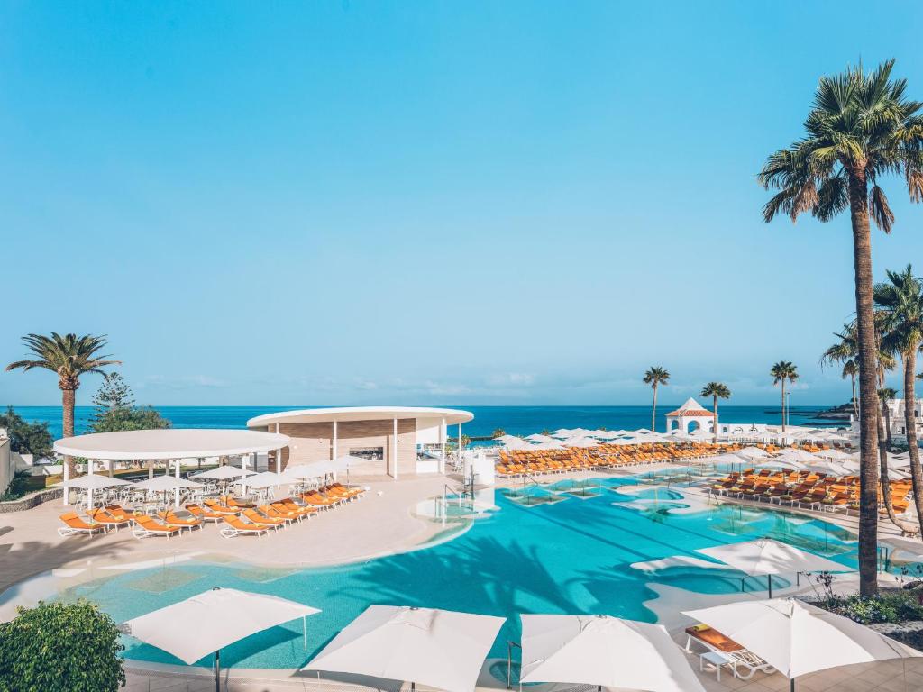 uitzicht op een zwembad met parasols en de oceaan bij Iberostar Selection Sábila - Adults Only in Adeje