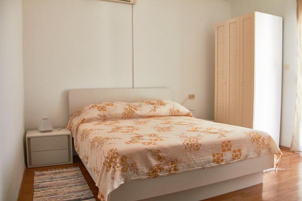 um quarto branco com uma cama e uma mesa de cabeceira em One bedroom apartment Šimičić em Rab
