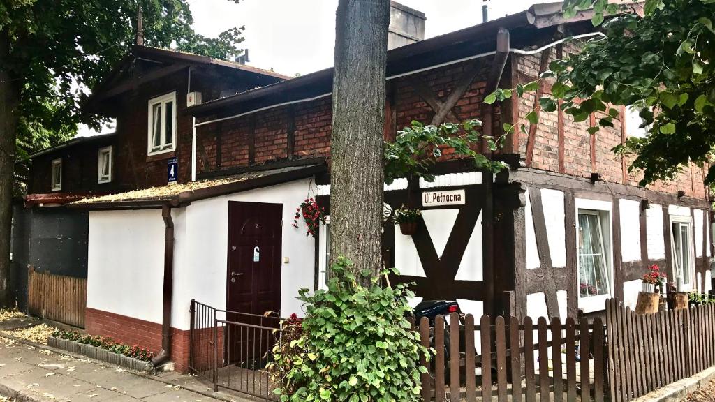 une maison blanche et noire avec une clôture en bois dans l'établissement Fisherman's Surfhouse, à Gdańsk
