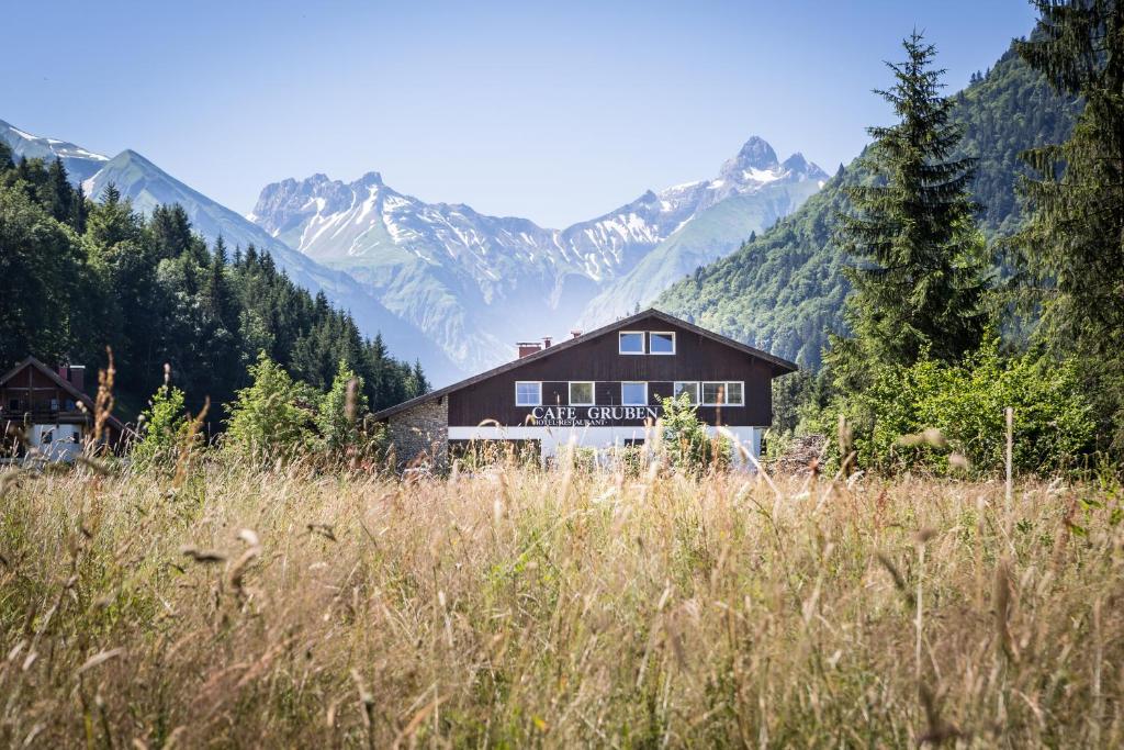 una casa in un campo con montagne sullo sfondo di Gästehaus Gruben a Oberstdorf