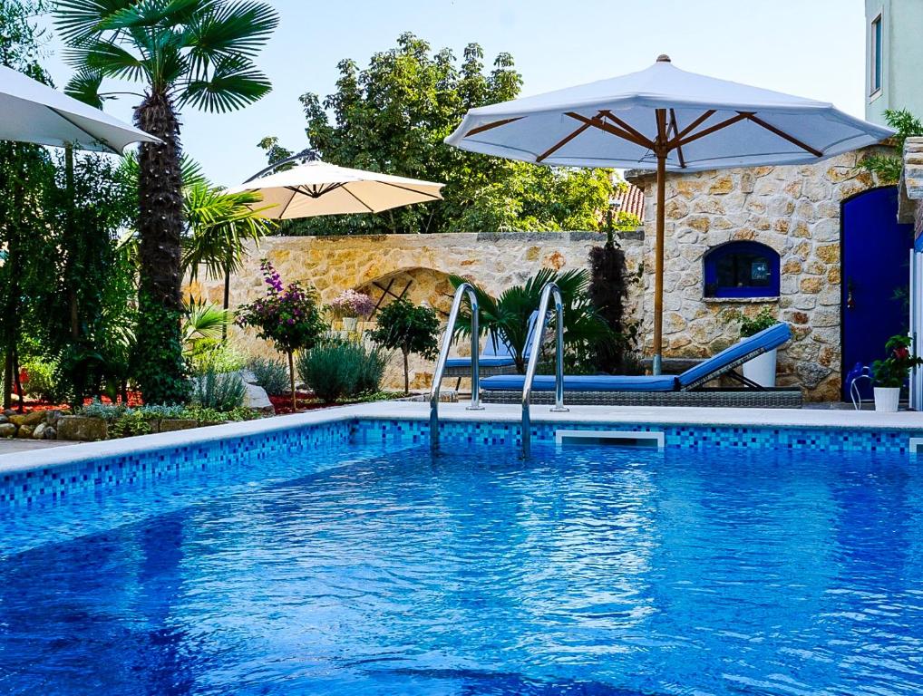 a swimming pool with two chairs and an umbrella at Vila Vinci 1906 in Vrsar