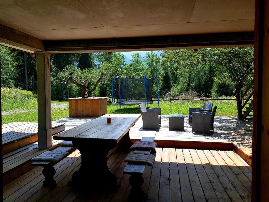 eine Holzterrasse mit einem Holztisch und Bänken in der Unterkunft Entre Giffre et Valentine in Verchaix