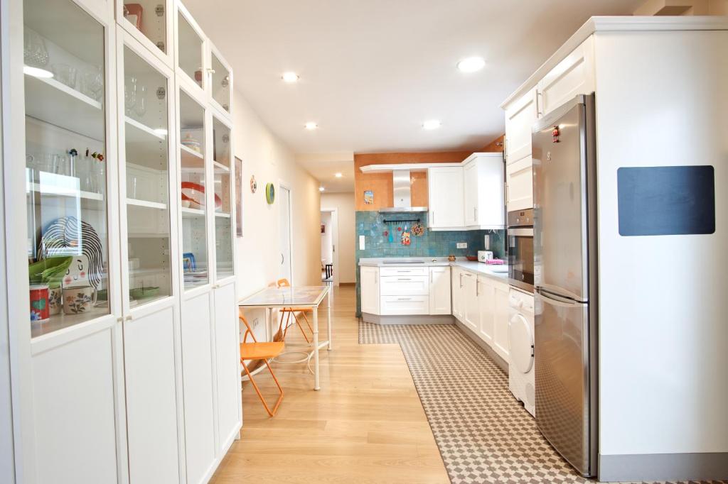 Una cocina con gabinetes blancos y un refrigerador de acero inoxidable. en Rodrigo de Triana Courtyard by Valcambre, en Sevilla