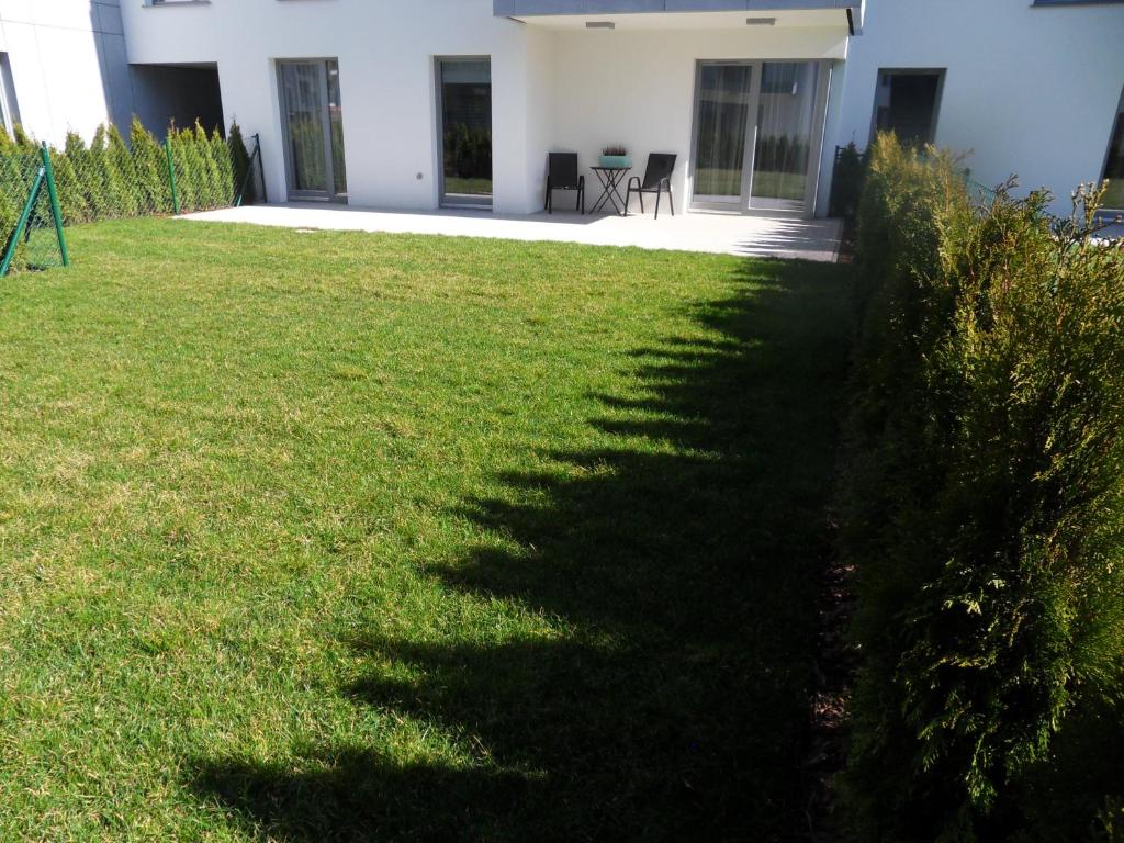 a hedge in front of a house with a lawn at Lighthouse Apartment Nadmorze - 150 m od morza, ogródek, garaż in Gdańsk
