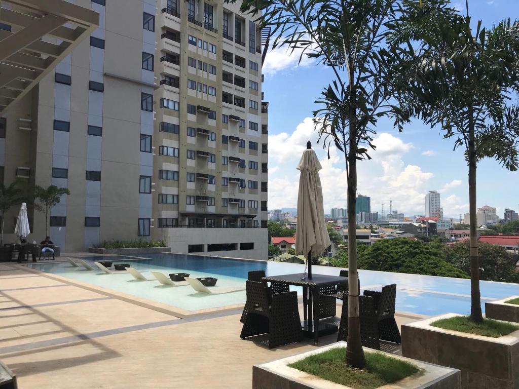 a swimming pool with a table and a umbrella at The Persimmon Studios Near Ayala and SM City Cebu in Cebu City