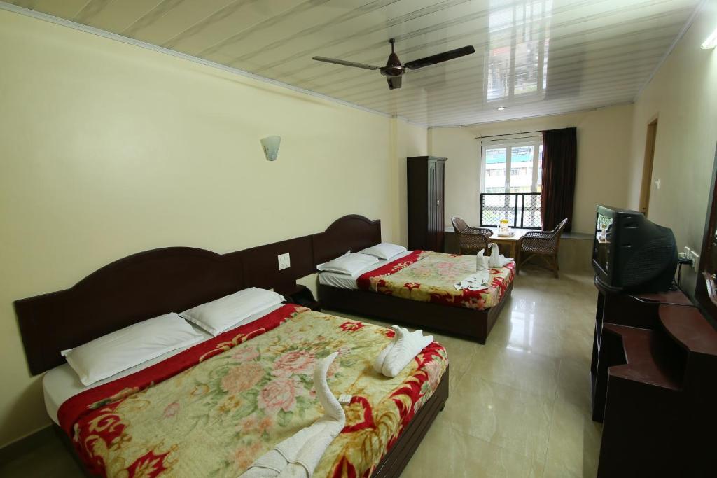 a hotel room with two beds and a television at Jays Inn in Munnar