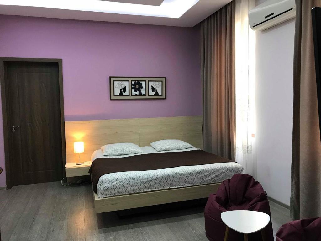 a bedroom with a bed and a purple wall at Smak in K'obulet'i