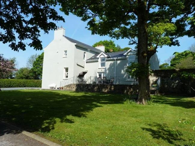 una gran casa blanca con un árbol en el patio en Hartley House B&B en Carrick on Shannon