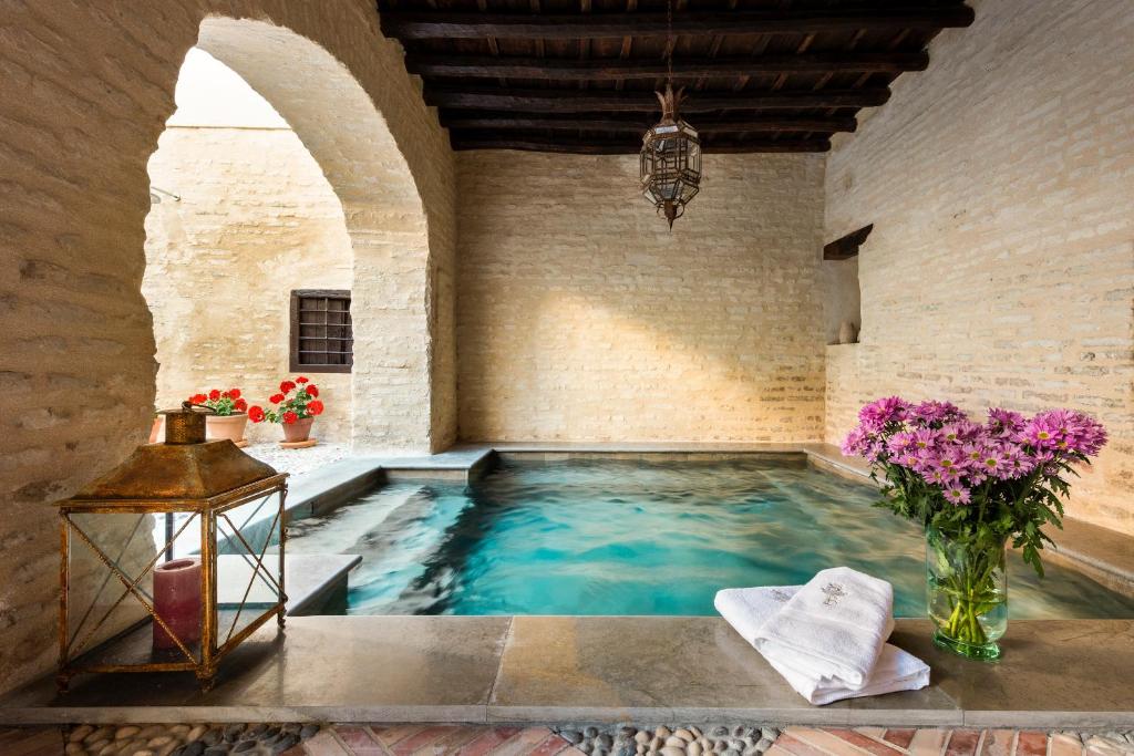 uma piscina num edifício com flores num quarto em Palacio Bucarelli em Sevilha