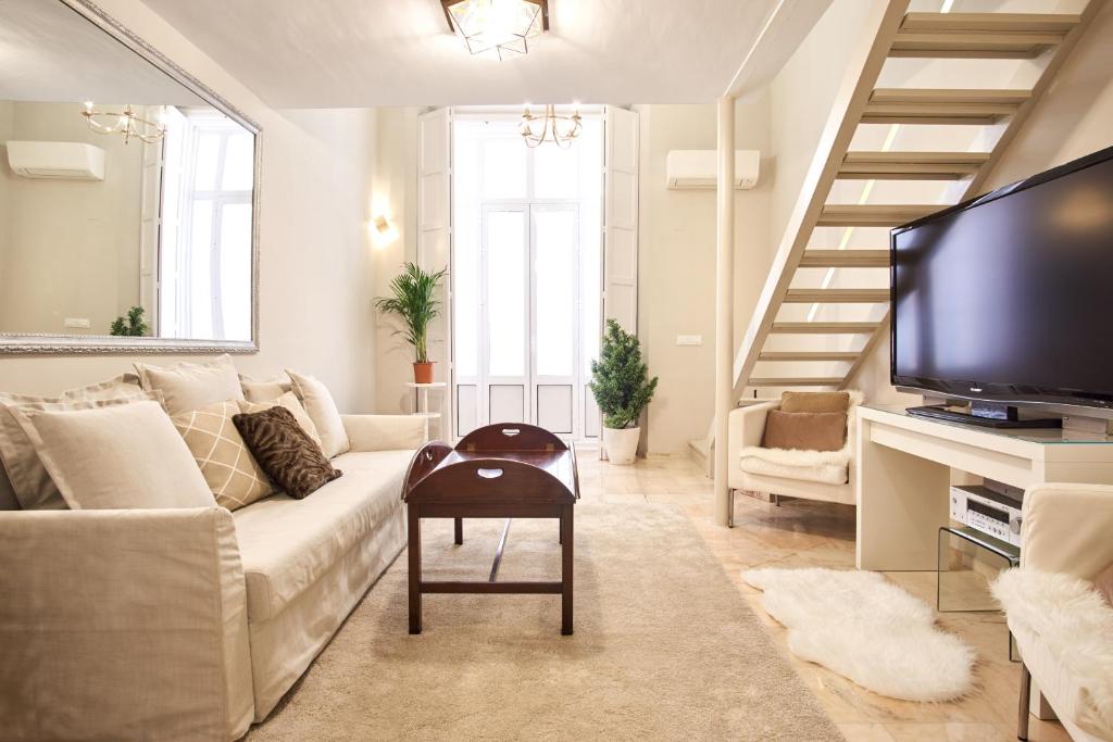 ein Wohnzimmer mit einem weißen Sofa und einem TV in der Unterkunft Pajaritos Palace by Valcambre in Sevilla