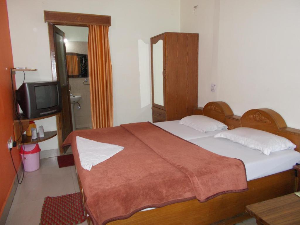 a bedroom with a bed and a tv in it at Premier rooms with Rooftop Terrace Restaurant in Nainital