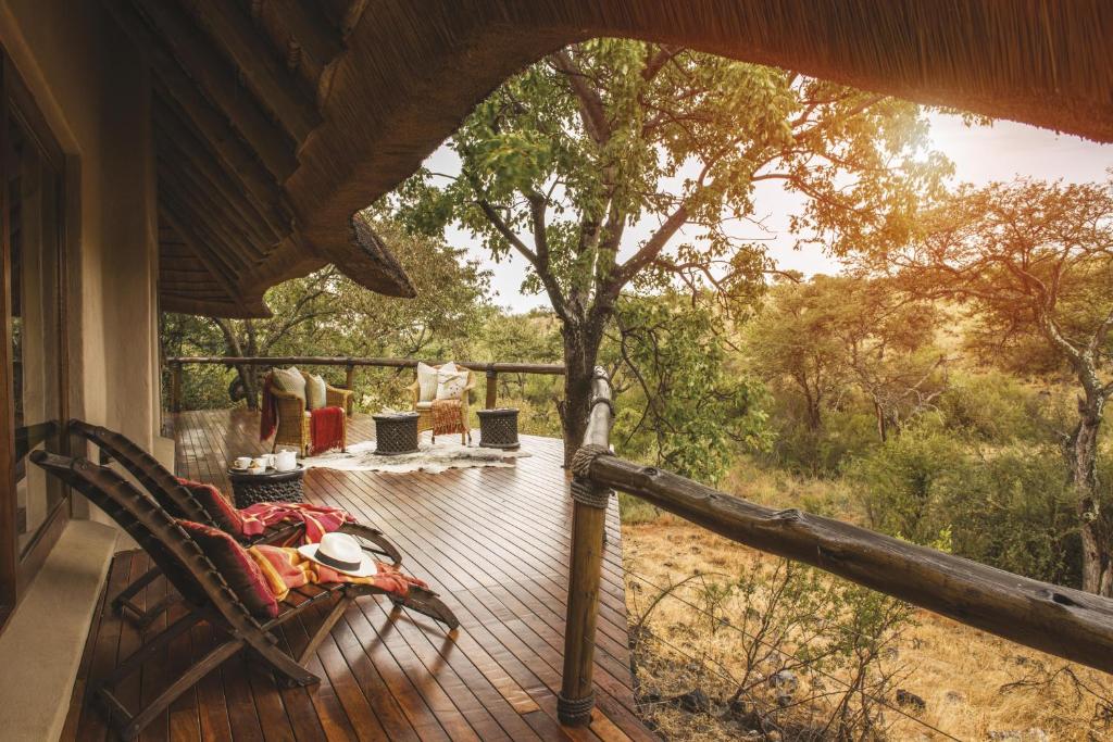 eine Veranda eines Hauses mit einer Bank auf dem Deck in der Unterkunft Tuningi Safari Lodge in Madikwe Game Reserve