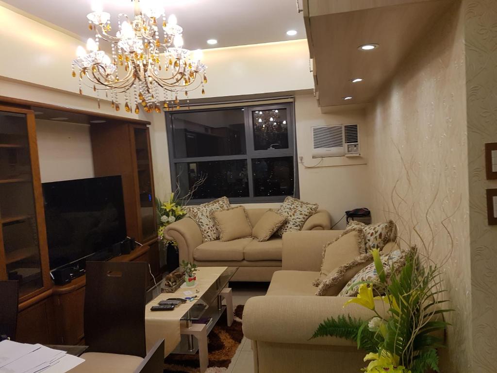 ein Wohnzimmer mit 2 Sofas und einem Kronleuchter in der Unterkunft KC 2-Bedroom 1 at Horizon 101 Cebu in Cebu City