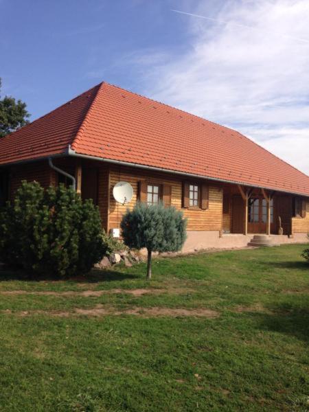 a house with a red roof and a tree in the yard at Mézesfészer apartman in Cserkút