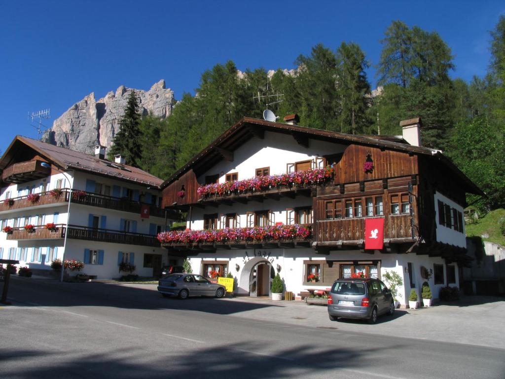 a building in the mountains with cars parked in front of it at Hotel Al Larin in Cortina dʼAmpezzo