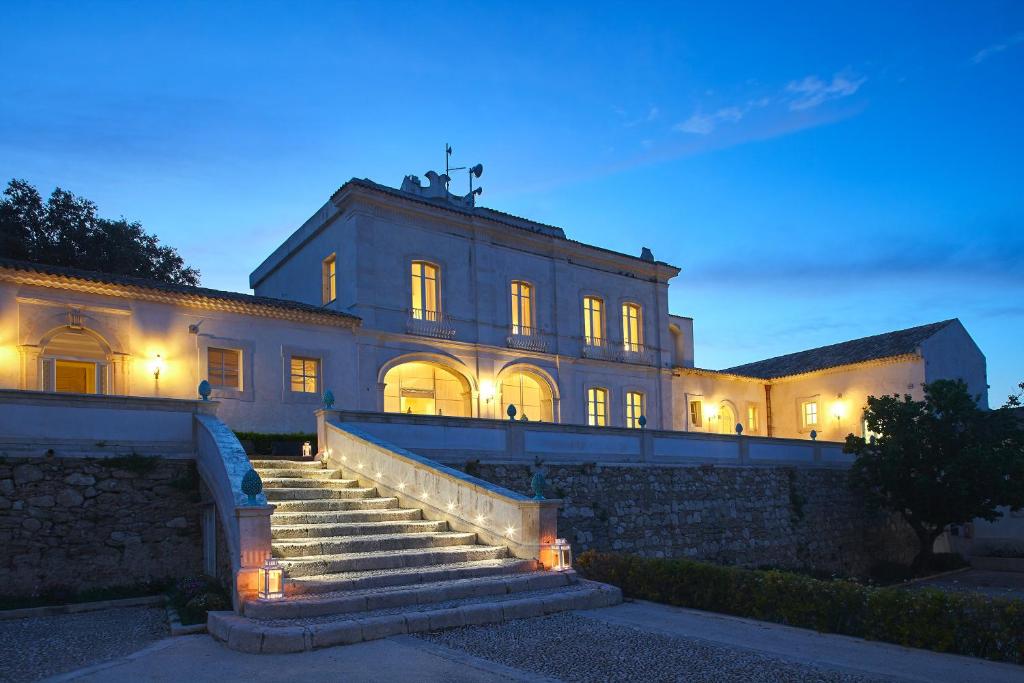 ein großes Gebäude mit einer Treppe davor in der Unterkunft Borgo di Luce I Monasteri Golf Resort & SPA in Syrakus