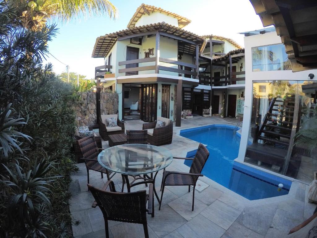 un patio con mesa de cristal y sillas junto a una casa en Pousada Do Capitão, en Arraial do Cabo