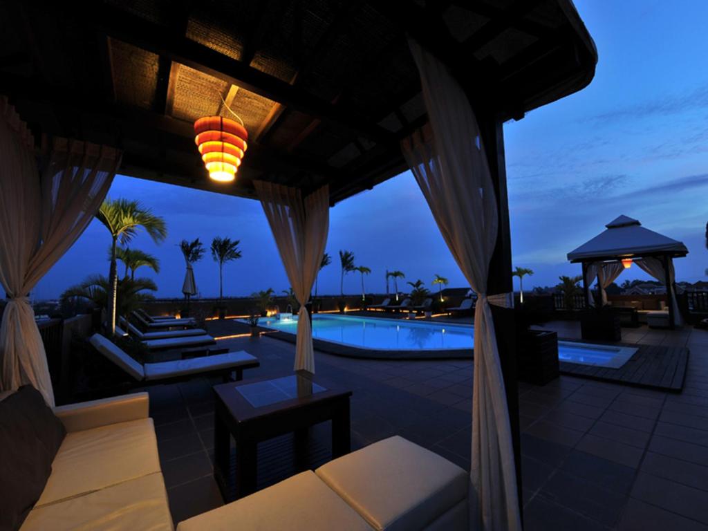 a resort patio with a swimming pool at night at City River Hotel in Siem Reap