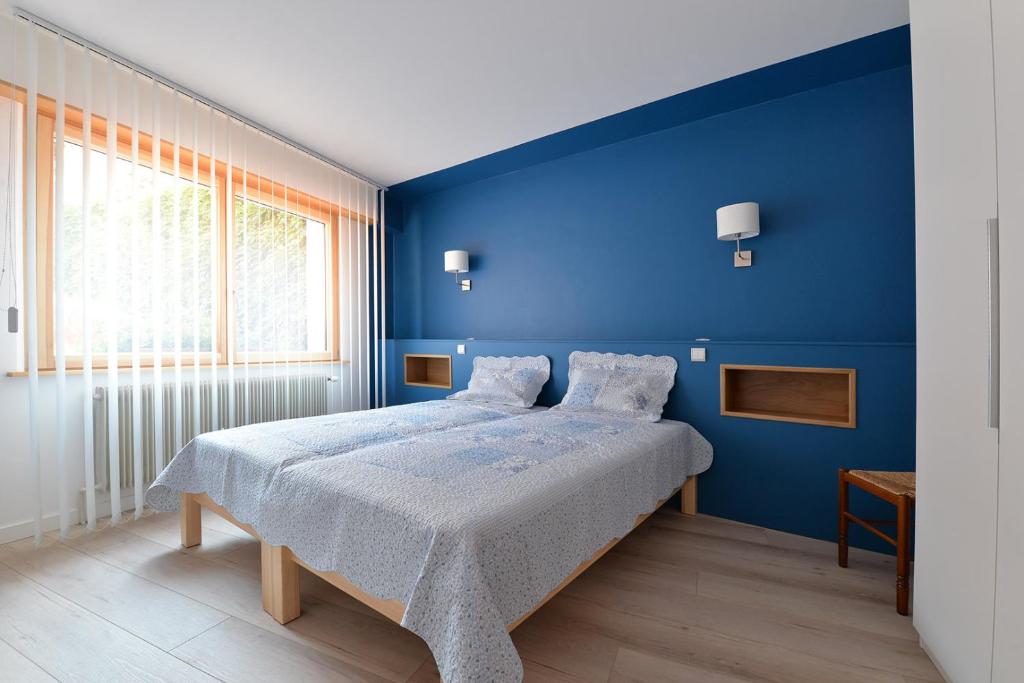 a blue bedroom with a bed and a window at S'Harzala Bleu in Bergheim