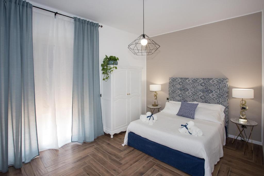 um quarto com uma cama branca e cortinas azuis em AmaSi Affittacamere em Siracusa