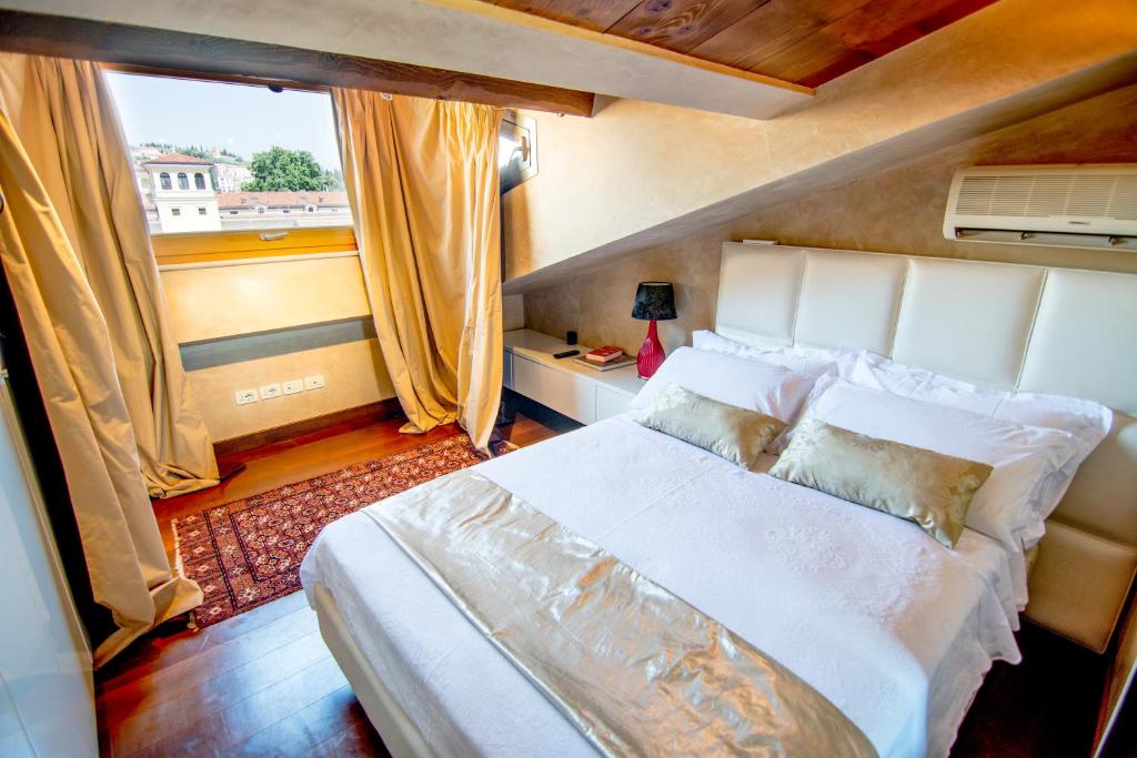 una camera da letto con un grande letto bianco e una finestra di Opera Luxury Apartment a Verona
