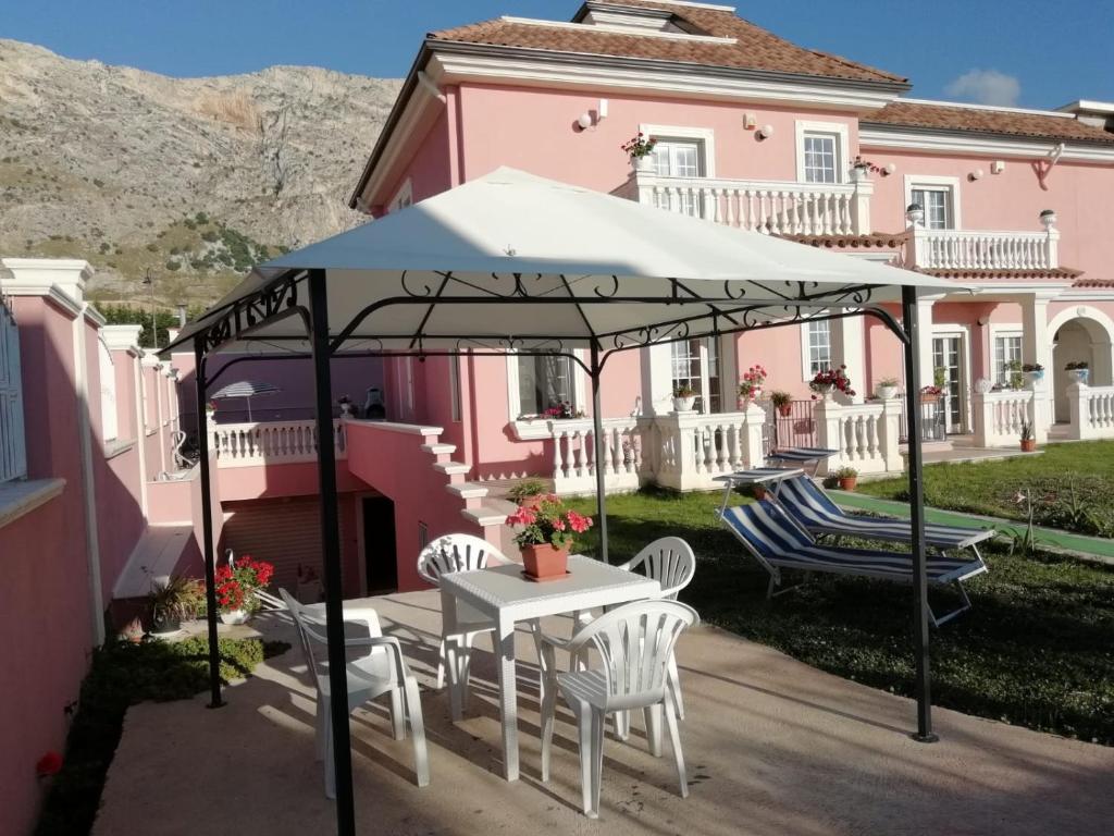 a table and chairs under an umbrella in front of a pink house at Casa Vacanze Villa Rosa Beach in Isola delle Femmine