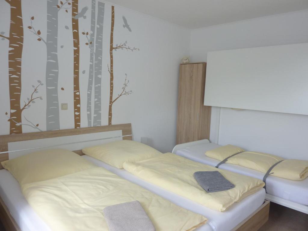 2 Betten in einem Zimmer mit Bäumen an der Wand in der Unterkunft Ferienwohnung Edelmann in Markersbach